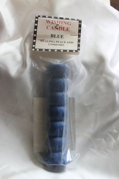 a blue candle wrapped in plastic on top of a white sheet