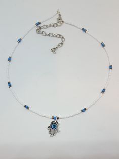 "Evil Eye Choker A fun trendy version of the ever popular Boho Choker, A Stunning whimsical white choker with focal Evil Eye charm. Choker made with 2/0 mm white colored glass seed beads, blue glass seed beads, pewter colored glass beads and quality jewelry findings. All beads are quality glass, and metal, purchased at exclusive bead shops. Choker measures 14\" with 3 inch extension chain. Jewelry items are secured with split rings to insure durability. This designer choker will look super nice White Bohemian Beaded Necklace With Evil Eye, Bohemian White Beaded Necklace With Evil Eye, Adjustable White Beaded Necklace With Evil Eye, White Evil Eye Jewelry For Festivals, Evil Eye Choker, Pretty Face Mask, White Choker, Choker Designs, Blue Mask