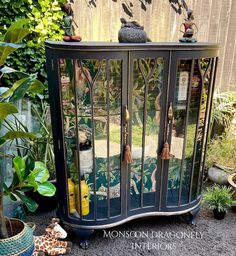 this is an image of a glass cabinet in the garden with plants and other things around it