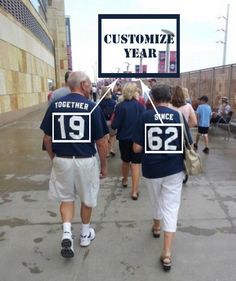 two men in blue shirts walking down the street with people wearing white shorts and black shoes