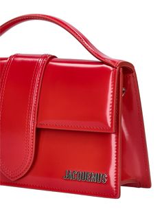 Find JACQUEMUS Le Grand Bambino Leather Top Handle Bag on Editorialist. The JACQUEMUS Le Grand Bambino Top Handle Bag features a detachable strap, a single top handle, a front flap with a magnetic closure, a metal logo detail, one back patch pocket, and a cotton lining. It measures 13cm in height, 23.5cm in width, and 6cm in depth. The strap drop is 50cm and the handle drop is 4cm. Luxury Red Bags With Adjustable Handle, Red Evening Bag With Adjustable Handle, Jacquemus Le Grand Bambino, Neon Bag, Suede Tops, Metallic Bag, Bag Light, Back Patch, Metal Logo