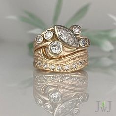 two gold wedding rings with diamond accents on white table top next to green leafy plant