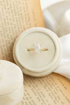 an engagement ring sitting on top of a book next to a white box with a diamond in it