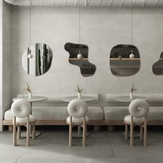 three circular mirrors are hanging on the wall above two tables with chairs in front of them