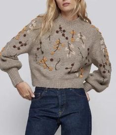 a woman is wearing a sweater with flowers on the front and back, while she has her hands on her hips