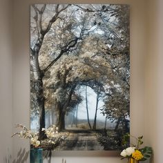 a painting is hanging on the wall next to a table with flowers and vases