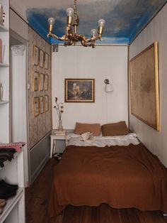 a bedroom with a bed and paintings on the walls, along with a chandelier