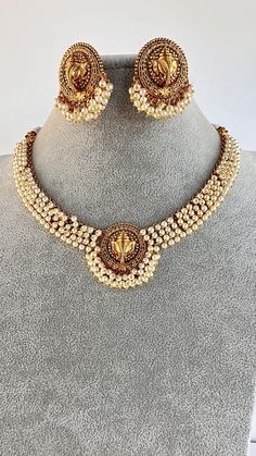 This exquisite piece of craftsmanship comes from our Traditional collection. Very Elegant and stylish, this necklace can be paired with any Attire depending upon the occasion and the theme. Finish: 24 grams gold finish Necklace Fastening: Adjustable Dori Earring Fastening: Push Back Contains: 1 necklace, 1 pair of earrings Luxury White Temple Jewelry Danglers, Luxury Traditional Temple Necklace For Ceremonial Occasions, Luxury Temple Jewelry Mangalsutra For Wedding, Affordable Temple Jewelry For Diwali, Ganesha Temple, Guttapusalu Necklace, Jewelry Indian Wedding, Temple Jewelry, South Indian Jewelry