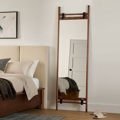 a bed sitting next to a mirror in a bedroom on top of a hard wood floor