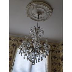 a chandelier hanging from the ceiling in a room with floral wallpaper and curtains