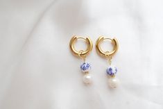 Discover timeless sophistication with our Porcelain Pearl Hoop Earrings. The intricate charm - a harmonious blend of elegant porcelain and lustrous pearls is added onto an 18k gold plated stainless steel hoop, perfect for both everyday wear and special occasions.  Hoop diameter: 16mm Materials: 18K gold-plated stainless steel Packaging: Delivered in a pouch, ready for gift-giving. Pearl Hoop Earrings, Huggie Hoop Earrings, Jewelry Earrings Hoops, Gold Hoop, White Ceramics, 18k Gold, Gold Plate, Jewelry Earrings, Hoop Earrings