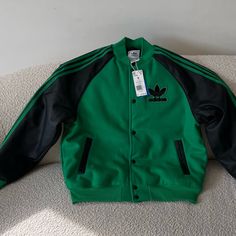 Almost Out Of Stock. A Few Pieces In Farfetch For $273. This Lightweight Bomber Jacket Features Bold Color Combos And A Unique Chenille Trefoil Badge. Beyond The Way It Looks, You Can Count On The Loose Layer-Ready Shape And Excellent Insulation Properties When The Temperature Dips. Now That's What We Mean By Fashion-Meets-Function. Loose Fit Full Snaps With Ribbed Bomber Collar Shell: 55% Recycled Polyester, 40% Acrylic, 5% Wool Single Jersey Sleeves: 100% Polyurethane Leather Inside Welt Pocke Adidas Green Outerwear For Streetwear, Adidas Green Outerwear For Winter, Adidas Green Winter Outerwear, Red Adidas Jacket, Adidas Jacket Women, Rita Ora Adidas, Sport Sweater, Adidas Windbreaker, Adidas Track Jacket