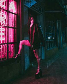 a woman standing in front of a window with neon lights