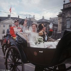 the bride and groom are riding in a horse - drawn carriage down the city street