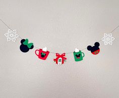 mickey mouse tea cups are hanging on a string with snowflakes and paper stars