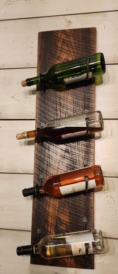 four wine bottles are lined up on a wooden board