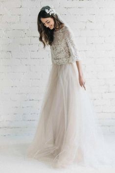 a woman in a white dress standing next to a brick wall wearing a tiara