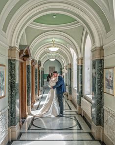 a bride and groom are kissing in an ornate hallway at the end of their wedding day