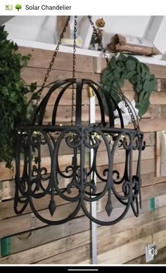 a black metal light fixture hanging from a wooden wall next to a green planter