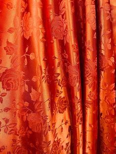 an orange curtain with red flowers on it