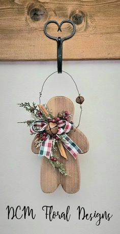 a wooden teddy bear hanging on a wall with the words ncm floral designs written below it