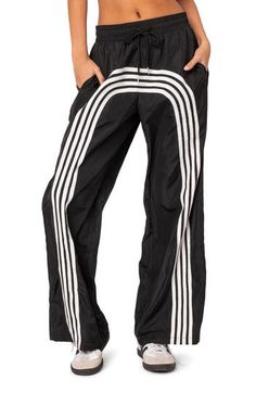 Sporty stripes race around the wide legs of these tie-waist track pants. Elastic/drawstring waist Side pockets 100% polyester Machine wash, dry flat Imported Sporty Striped Sports Bottoms, Striped Sporty Bottoms For Sports, Sporty Striped Bottoms For Sports, Casual Bottoms With Signature Stripes For Streetwear, Casual Streetwear Bottoms With Signature Stripes, Sporty Black Parachute Pants For Summer, Sporty Striped Pants With Side Stripes, Sports Wide Leg Pants With Contrast Stripes, Summer Sports Wide-leg Parachute Pants