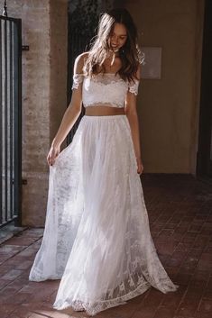 a woman wearing a white two piece wedding dress