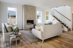 a living room filled with furniture and a fire place under a stair case next to a window