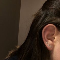 a close up of a person with ear piercings on their ears and behind them is a wall