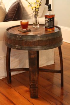 a wooden barrel table sitting on top of a hard wood floor next to a couch