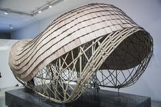 a large wooden boat sitting on top of a black table next to a white wall