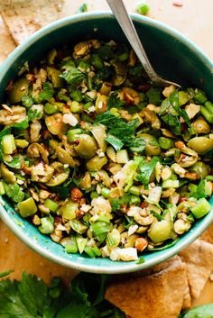 a green bowl filled with food next to tortilla chips and cilantro