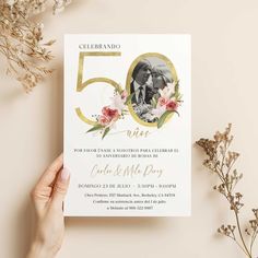 a hand holding up a 50th birthday card with flowers and an image of two people