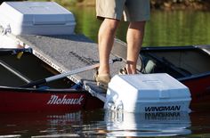 a man standing on top of a boat in the water next to a box and oars