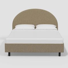 a bed with a beige headboard and white pillows on top of it, in front of a gray background