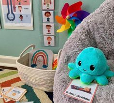 a blue stuffed animal sitting on top of a chair next to a basket filled with toys