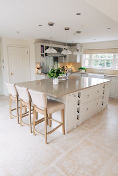 a large kitchen with an island in the middle and four stools at the end