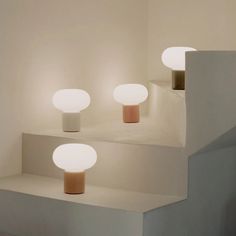 three white and pink lights sitting on top of some steps in a room next to each other