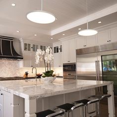 a large kitchen with an island and two stools in front of the counter top