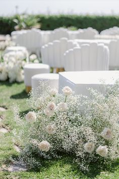 white flowers and baby's breath are on the grass in front of rows of chairs