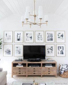 a living room with pictures on the wall and a television in the center, along with a coffee table