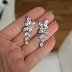 a pair of diamond earrings in the palm of someone's hand