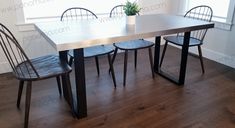 a dining table with four chairs and a potted plant in the middle on top