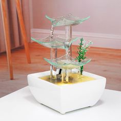 a white table topped with two glass vases filled with water and plants on top of it