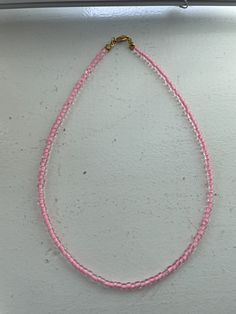 a pink and clear beaded necklace, perfect for summer!! Adjustable Single Strand Pink Beaded Necklace, Pink Choker Necklace For Summer, Pink Tiny Beads Necklace For The Beach, Pink Beaded Necklace For Beach With Colorful Beads, Pink Colorful Beaded Necklace For The Beach, Pink Tiny Beads Choker Necklace, Pink Beaded Choker With Round Beads, Pink Choker With Round Tiny Beads, Pink Round Beaded Necklaces For Beach