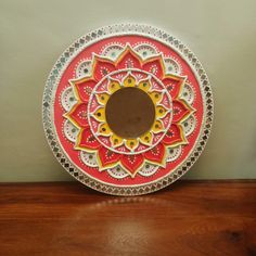 a red and yellow plate sitting on top of a wooden table next to a wall