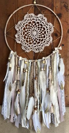 a white dream catcher hanging on a wooden wall