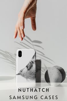 a hand reaching for an iphone case with a photo of a wolf on it and the words, nuthatch phone cases