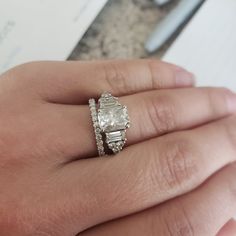 a woman's hand with a ring on it and an engagement band in the middle