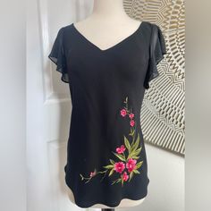 Excellent Condition! Never Worn. Beautiful Black Blouse With Floral Embroidery, Short Sleeves, V-Neckline. 100% Polyester. Chest: 28”. Length: 25” Black V-neck Tops With Floral Embroidery, Black V-neck Blouse With Floral Embroidery, Elegant V-neck Blouse With Floral Embroidery, Elegant Floral Print V-neck Top, Elegant V-neck Floral Print Tops, Chic V-neck Tops With Floral Embroidery, Chic V-neck Top With Floral Embroidery, Black V-neck Top For Spring, Black V-neck Top With Floral Embroidery